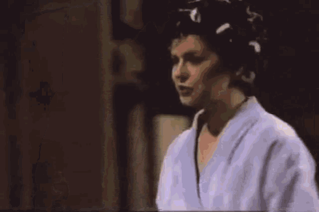 a woman with curlers in her hair is wearing a bathrobe