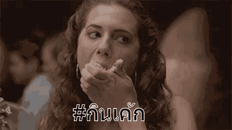 a woman with curly hair is eating a piece of food with her hands .