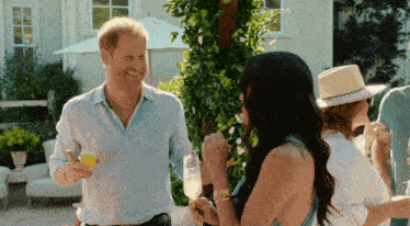 a man in a white shirt is holding a glass of champagne and talking to a woman