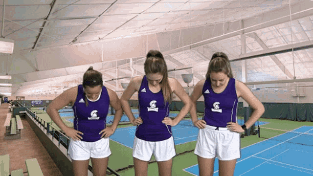 three female athletes wearing purple tank tops and white shorts with the word spartans on them