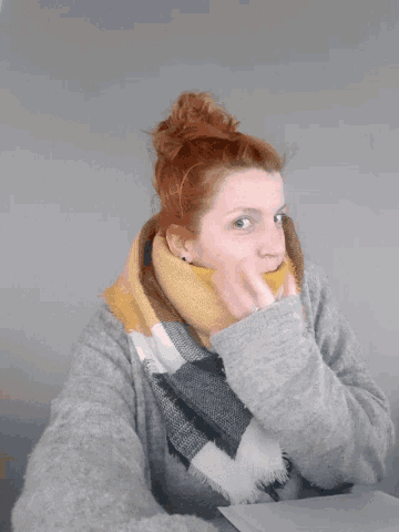 a woman wearing a grey sweater and a yellow and black scarf