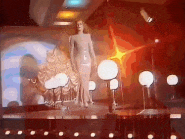 a woman in a long dress is standing on a stage
