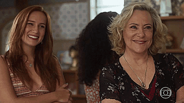 two women are standing next to each other and smiling in a room .