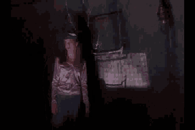 a woman in a purple shirt is standing in a dark room .