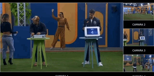 a group of people are standing around a table with a laptop on it in front of a sign that says camara 2
