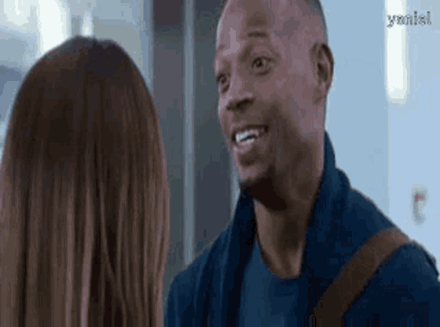 a man and a woman are smiling at each other in a hallway .
