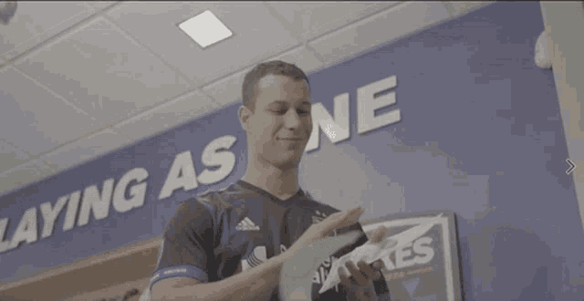 a man standing in front of a blue wall that says " ying as one "