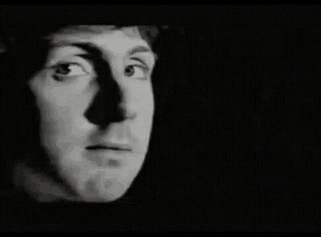 a close up of a man 's face in a black and white photo with a shadow on his face .