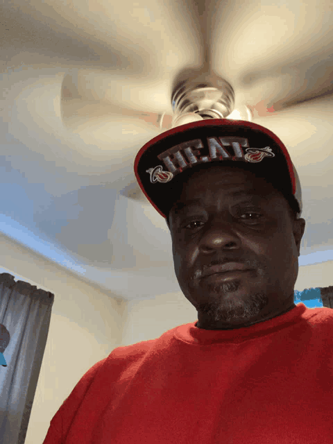 a man wearing a red shirt and a hat that says heat on it
