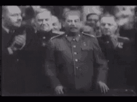 a man in a military uniform is standing in front of a crowd of men .