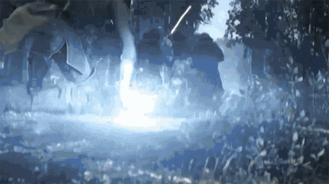 a person is standing in a dark forest with a blue light coming out of their hand