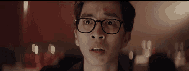 a close up of a person wearing glasses with a surprised look on his face