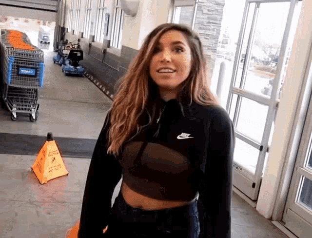 a woman wearing a black nike sweatshirt stands in front of a walmart cart