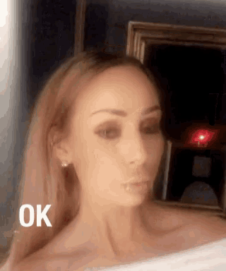 a woman taking a selfie in front of a mirror that says ok on the bottom