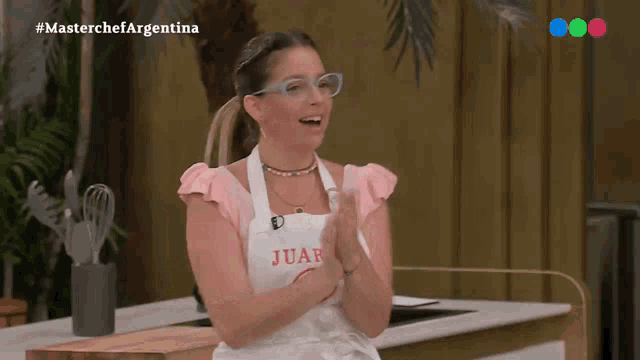 a woman wearing an apron that says juan is clapping her hands