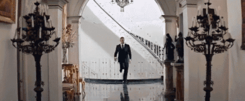 a man in a suit is running down a staircase in a hallway