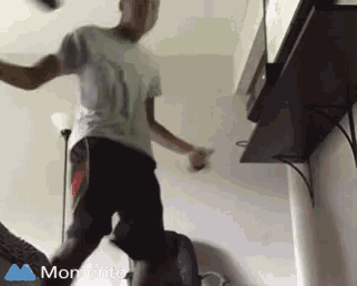 a boy is kicking a soccer ball in a room with a moments logo