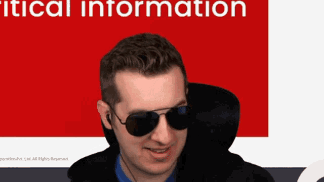a man wearing sunglasses and ear buds stands in front of a red background that says " critical information "