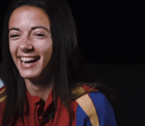 a woman with long hair is smiling and wearing a red and blue shirt
