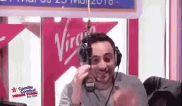 a man wearing headphones is sitting in front of a microphone in a radio studio .