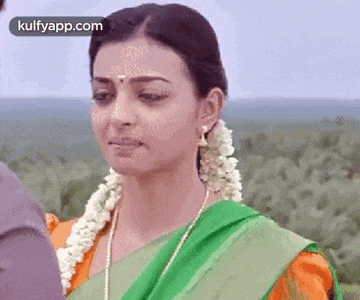 a woman in a green and orange sari is looking at a man .