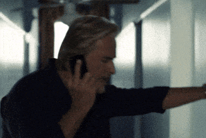 a man talking on a cell phone while standing in a hallway