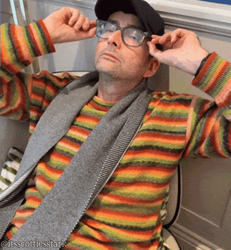 a man wearing glasses and a striped shirt is sitting on a chair