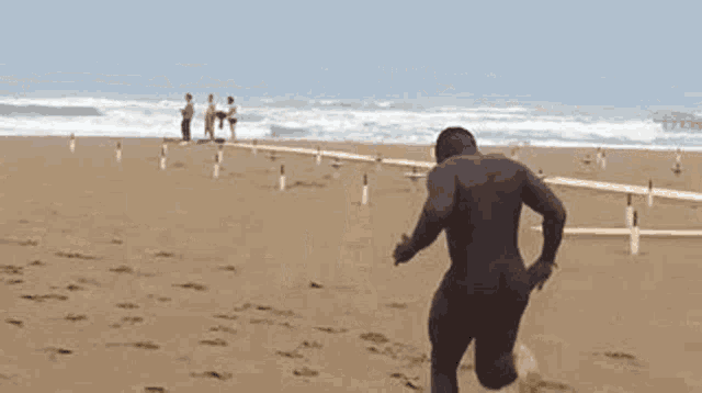 a man in a wetsuit is running on a sandy beach .