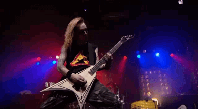 a man is playing a guitar on a stage while wearing a black shirt with a horse on it .