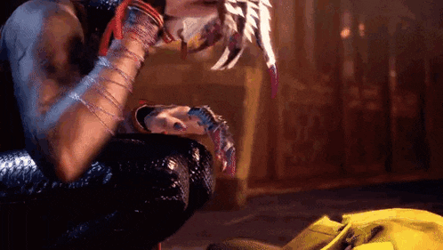 a man is kneeling down in a dark room with a feathered mask on his face .