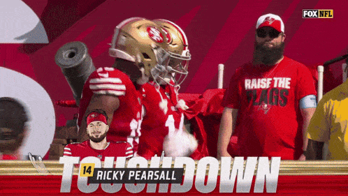 a man wearing a red shirt that says " raise the flags " stands next to a football player