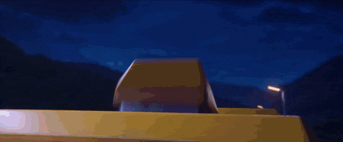 a woman with pink hair is sitting on the roof of a yellow vehicle
