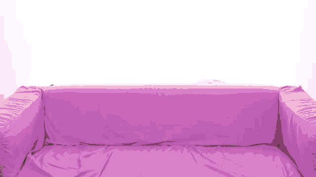 a man peeking over a purple couch cover