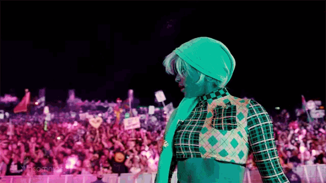 a woman in a plaid shirt is standing in front of a crowd of people at a concert .