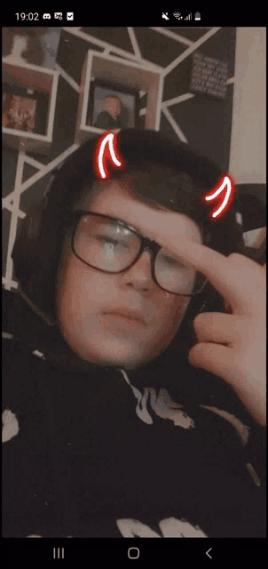 a young man wearing glasses and headphones has devil horns on his head