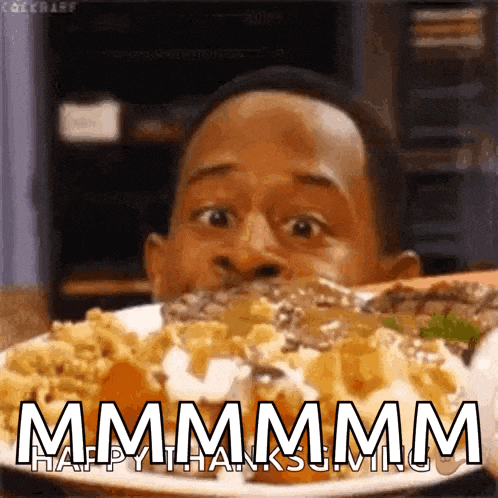 a man is eating a plate of food with the words `` mmmm happy thanksgiving '' written on it .