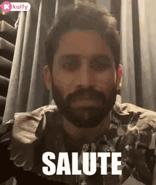 a man with a beard is making a salute gesture .