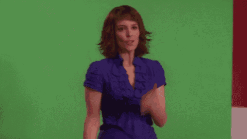a woman in a blue shirt is blowing a kiss in front of a green screen