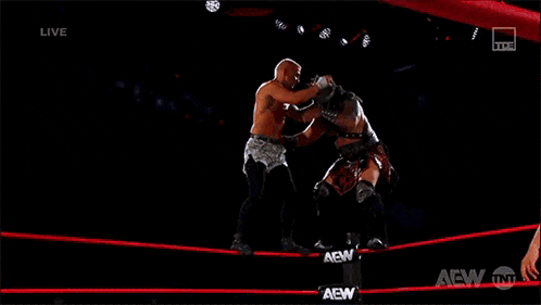 two wrestlers are fighting in a wrestling ring with the words live on the bottom of the screen .