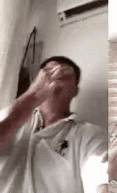 a man in a white shirt is taking a selfie in front of a mirror in a room .