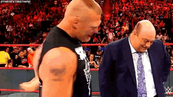a man in a suit and tie is standing next to another man in a black tank top .