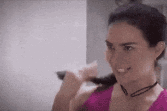 a woman in a pink tank top is smiling while holding a pink object in her hand .