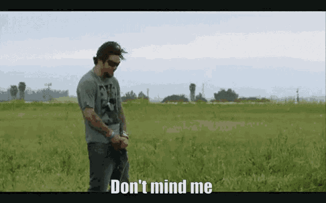 a man standing in a field with the words " don 't mind me " written on the bottom