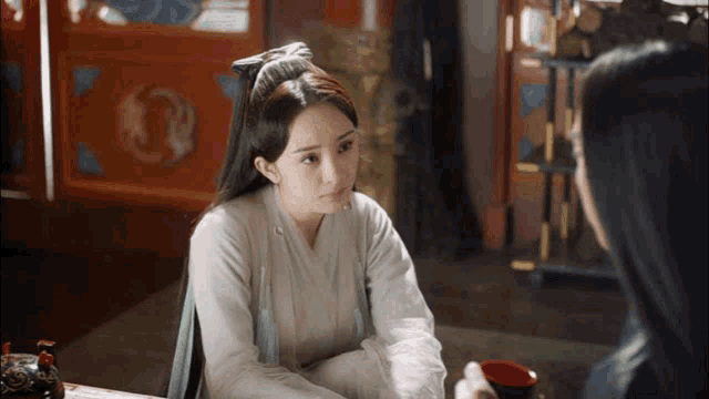 a woman is sitting at a table with another woman