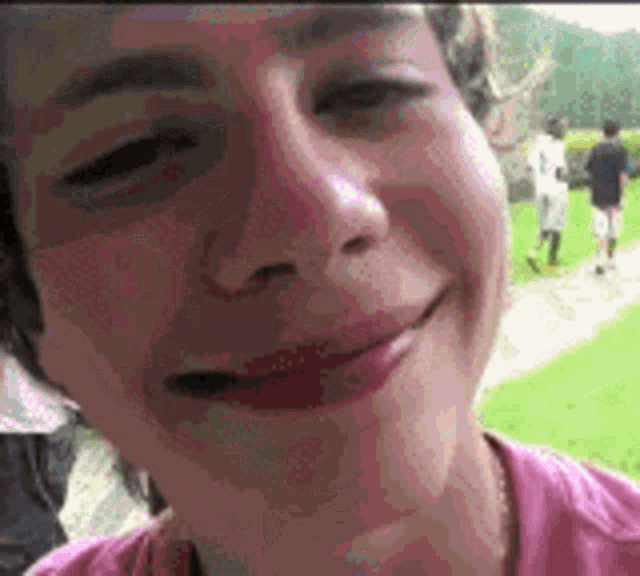 a close up of a person 's face with a pink shirt on .