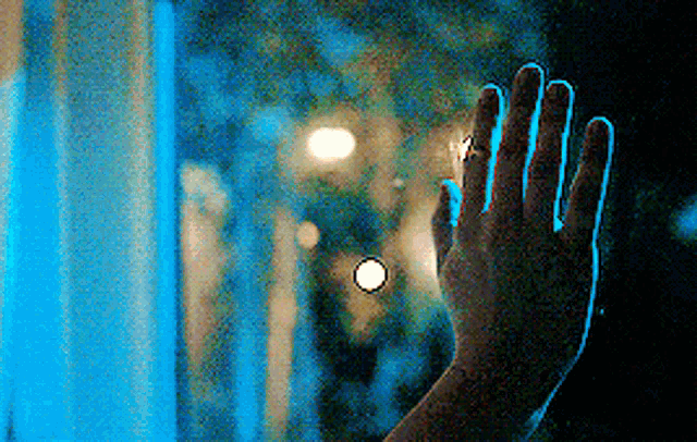 a person 's hand is visible against a window with a blue background