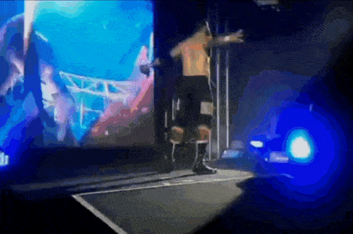 a man without a shirt is standing on a stage in front of a large screen with the number 11 on it .