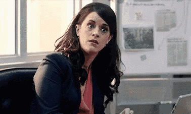a woman is sitting at a desk in front of a laptop computer and looking at the camera .