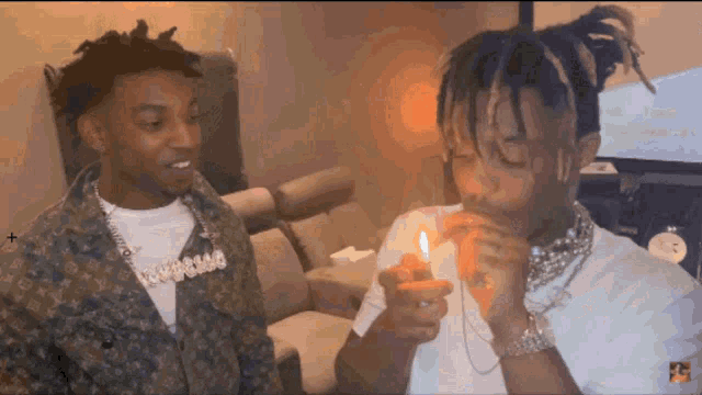 a man smoking a cigarette next to another man wearing a louis vuitton jacket