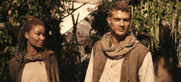 a man and a woman standing next to each other in a forest